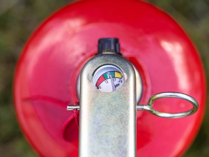 Close-up of a fire extinguisher pressure gauge showing charge level in the green zone