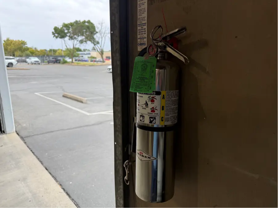 ABC fire extinguisher with current inspection tag mounted at a commercial building entrance