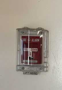 Fire alarm manual pull station with protective cover in a commercial building