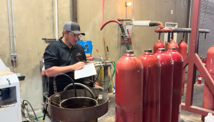 Technician recording data during a DOT hydrostatic test of high-pressure fire suppression cylinders at a Sacramento shop