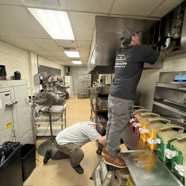 Two National Fire Systems technicians servicing a kitchen hood fire suppression system in a Sacramento commercial kitchen