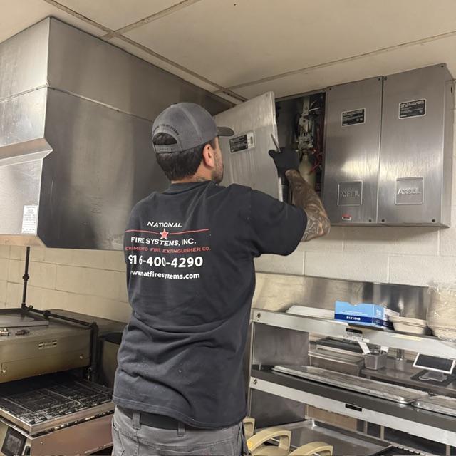 Technician inspecting a commercial kitchen hood fire suppression system during a Sacramento fire inspection